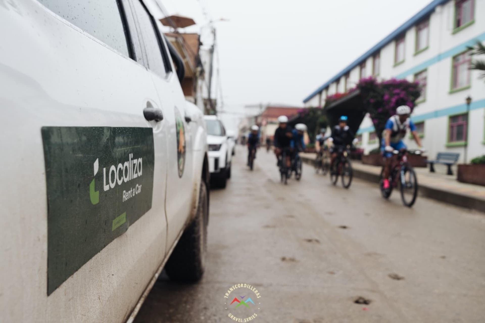 Vehículo de apoyo siguiendo ciclistas en calle de pueblo